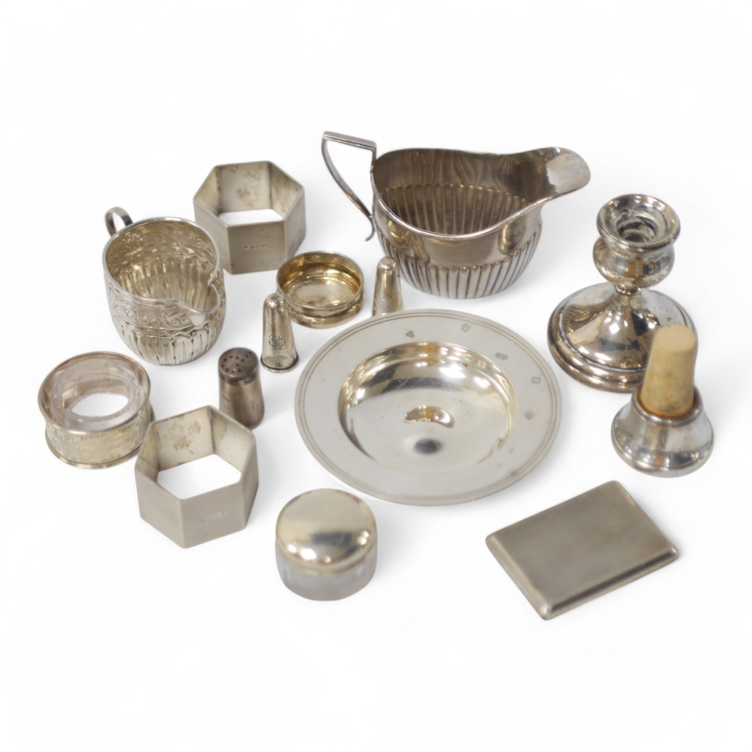 Small silver including two cream jugs, one demi-fluted, Birmingham, 1894, a dish, a dwarf candlestick, napkin rings, toilet jars, stopper, pepperette and extinguisher. Condition - poor to fair to good